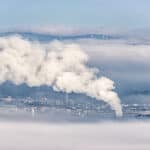 Smoke rising from a factory chimney, contributing to environmental and air quality issues.