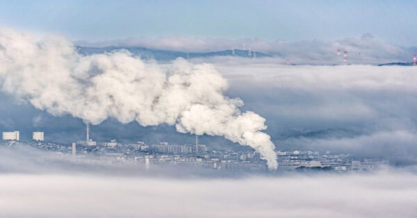Smoke rising from a factory chimney, contributing to environmental and air quality issues.