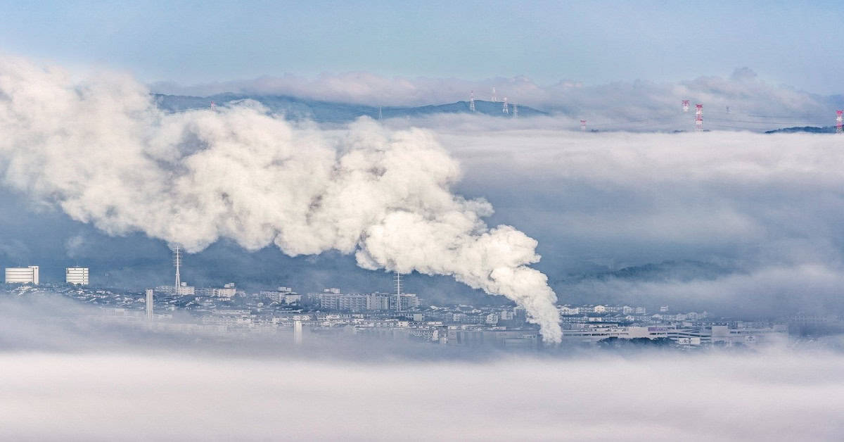Smoke rising from a factory chimney, contributing to environmental and air quality issues.