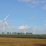 Wind turbines generating renewable energy in an open field under a clear sky.