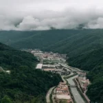 Forest ecosystem with river and human settlement highlighting the balance between nature and development