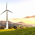 A wind turbine near a house in a serene natural setting, symbolizing environmental preservation efforts.