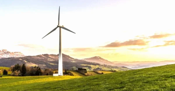 A wind turbine near a house in a serene natural setting, symbolizing environmental preservation efforts.