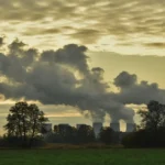 Factories releasing smoke with hazardous air pollutants impacting the surrounding environment.