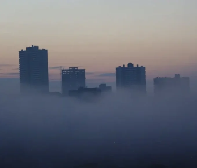 City skyline covered in dense smog, reflecting environmental pollution affecting air quality and climate